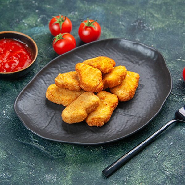 Close up view of tasty chicken nuggets in black plate tomatoes fork on dark background with free space